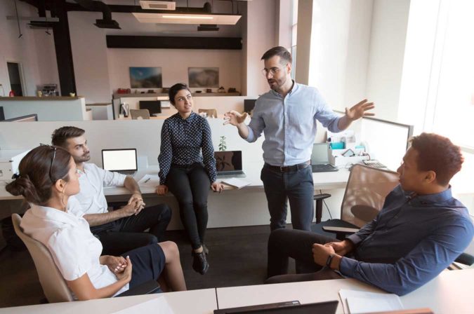 Five people in a circle having a discussion in an office setting
