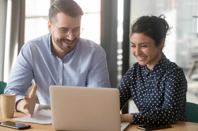 two colleagues having a discussion over a laptop in the workplace