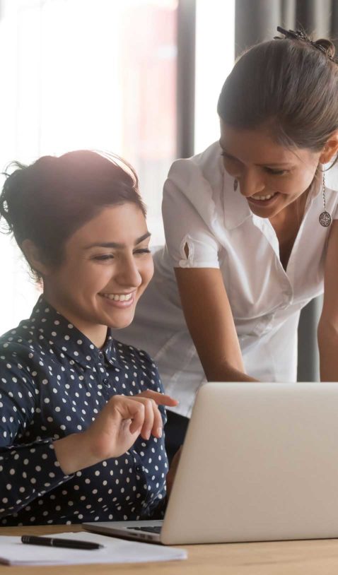 two women having a discussion over a laptop in the workplace