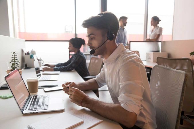 a man working on a laptop with a headset on